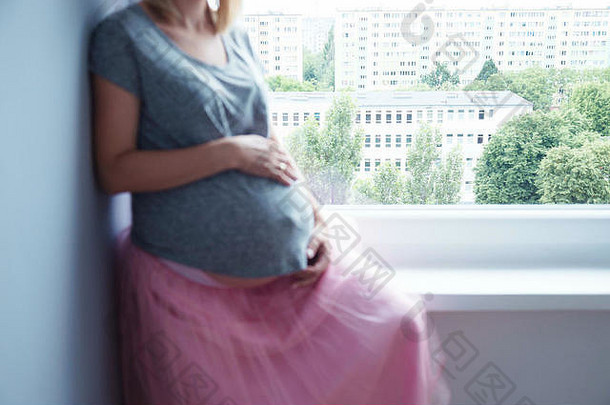 匿名怀孕了女人坐着窗口窗<strong>台</strong>上粉红色的裙子t恤焦点<strong>背景</strong>