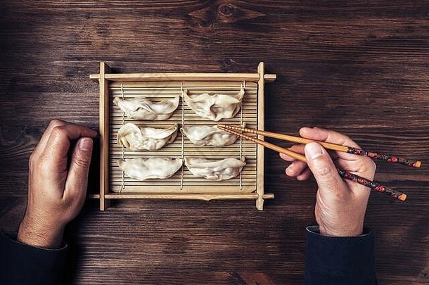 前视图手男人。筷子黑暗木表格准备好了<strong>吃饺子</strong>竹子托盘概念健康的东方快食物
