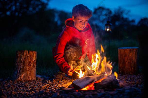 年轻的男孩微笑厨师棉花糖开放火同时野营
