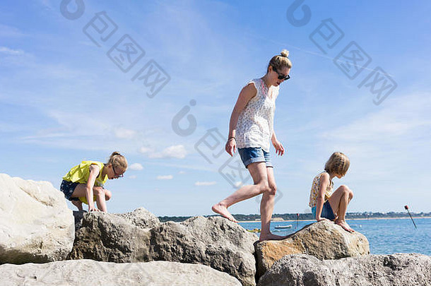 妈妈。女儿攀爬岩石海滩