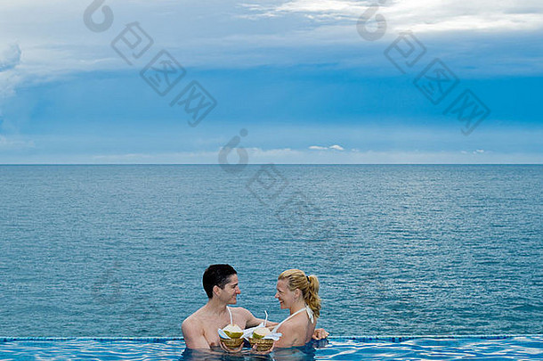 美丽的高加索人夫妇享受假期游泳池<strong>海边</strong>喝椰子牛奶