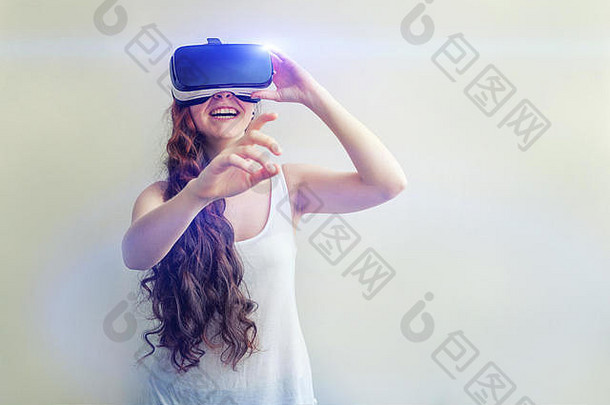 微笑年轻的女人穿虚拟现实眼镜头盔耳机白色背景智能手机虚拟现实护目镜技术模拟高新技术电子游戏概念