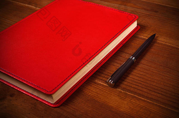红色的皮革日记笔木桌子上
