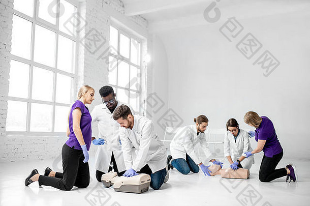 集团年轻的医务人员练习使人工呼吸医疗假人援助培训白色房间
