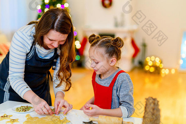 家庭妈妈。女儿烘焙饼干首页圣诞节夏娃漂亮的装饰房间壁炉圣诞节树灯背景