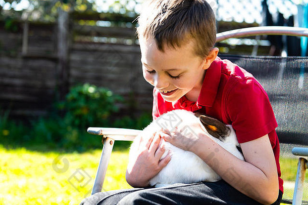 英俊的快乐微笑男孩自闭症埃斯博格综合症并发症状多动症拥抱最喜欢的宠物兔子花园首页