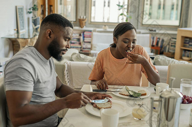 年轻的非洲美国夫妇坐着首页吃早餐