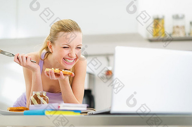 笑年轻的女人传播烤面包巧克力奶油研究厨房