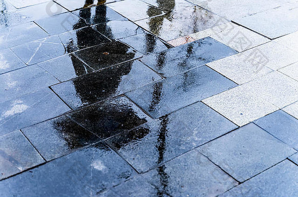 模糊的反射影子轮廓女人走伞行人城市湿街水坑秋天多雨的晚上