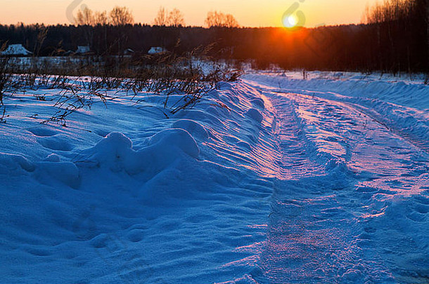日落黑暗蓝色的冬天雪地里国家路