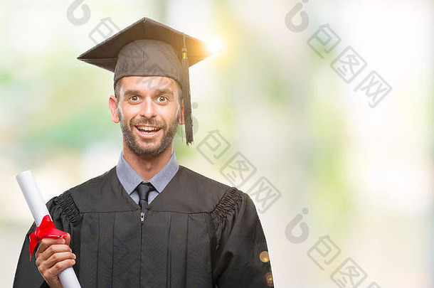 年轻的英俊的毕业男人。持有学位孤立的背景快乐脸站微笑自信微笑显示牙齿