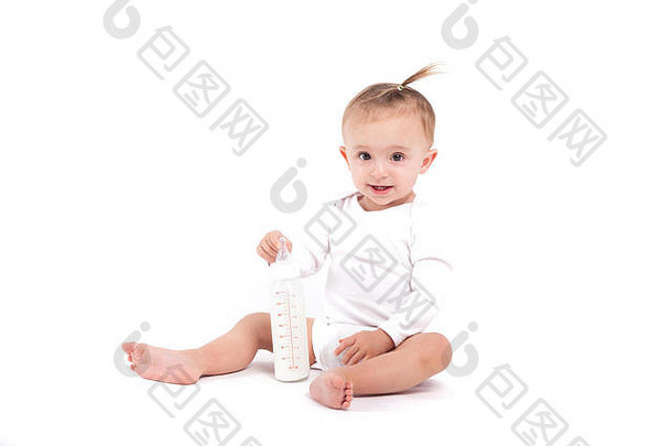 可爱的美丽的婴儿女孩白色衬衫坐持有牛奶瓶