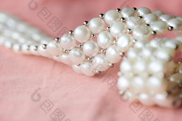美丽的白色珍珠项链珊瑚颜色纺织背景关闭