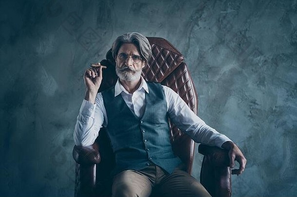 肖像有魅力的优雅的男人。老板公司老板坐椅子持有雪茄穿白色衬衫棕色（的）裤子裤子孤立的灰色颜色