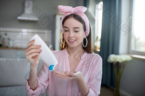 微笑漂亮的女孩粉红色的头巾倒乳液