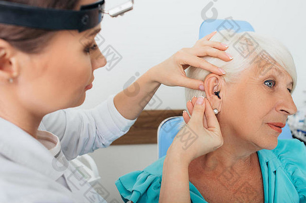 医生帮助上了年纪的女人插入听力援助