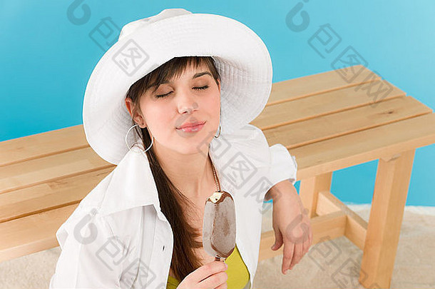 夏天女人少年享受巧克力冰棒棒糖坐着海滩
