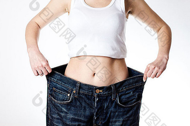 苗条的腰年轻的女人大牛仔裤显示成功的重量损失