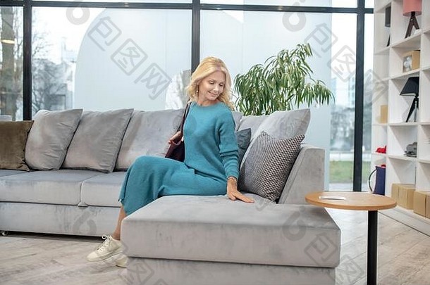 漂亮的女人长衣服坐着沙发商店