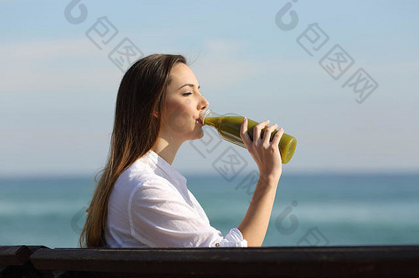 一边视图肖像女人喝蔬菜汁瓶海滩