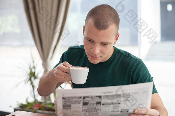 年轻的男人。坐着咖啡馆阅读报纸喝早....咖啡