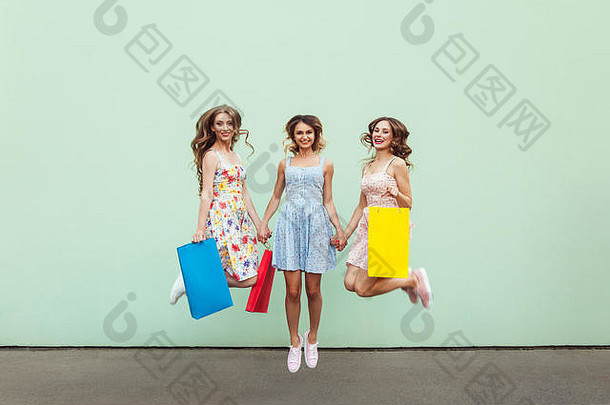 幸福美丽的朋友跳快乐色彩斑斓的包购物户外绿色墙