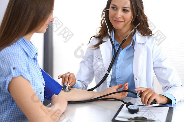 医生<strong>检查</strong>血压力女病人坐着桌子上医院办公室心脏病学医学健康护理概念