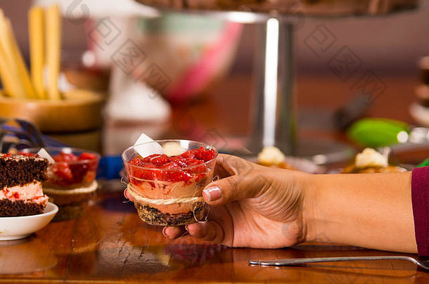手抓住美味的摩丝覆盖草莓一流的提出了内部小玻璃蛋糕块松饼背景糕点概念