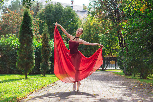 女人芭蕾舞女演员红色的芭蕾舞衣服跳舞尖端鞋子秋天公园