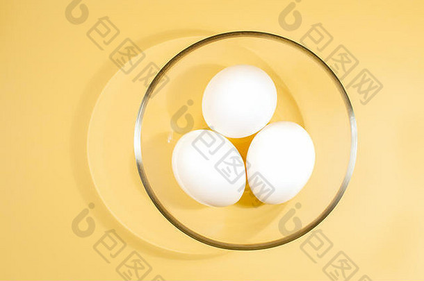 白色鸡蛋说谎轮透明的玻璃杯黄色的背景前视图