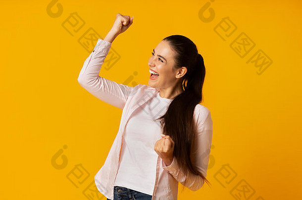 漂亮的浅黑肤色的女人女孩摇晃的拳头庆祝成功黄色的背景