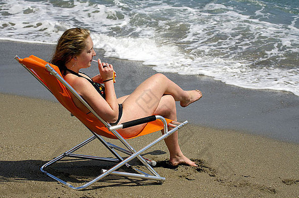 年轻的女人放松橙色汁海滩