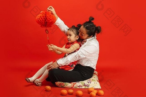 拥抱微笑快乐持有灯笼快乐中国人一年亚洲妈妈。女儿肖像红色的背景传统的服装庆祝活动人类情绪假期Copyspace