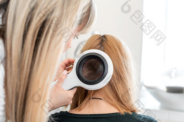 医生毛发学家皮肤科医生检查状态病人的头发头发根dermatoscope