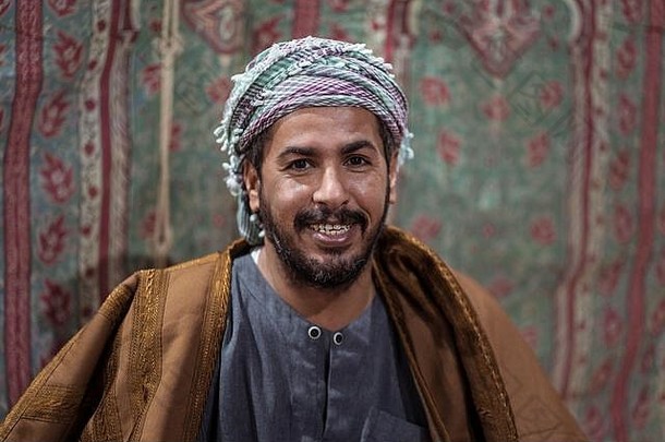 肖像贝都因人男人。穿传统的衣服祈祷念珠喝茶地毯沙特沙漠晚上沙特阿拉伯