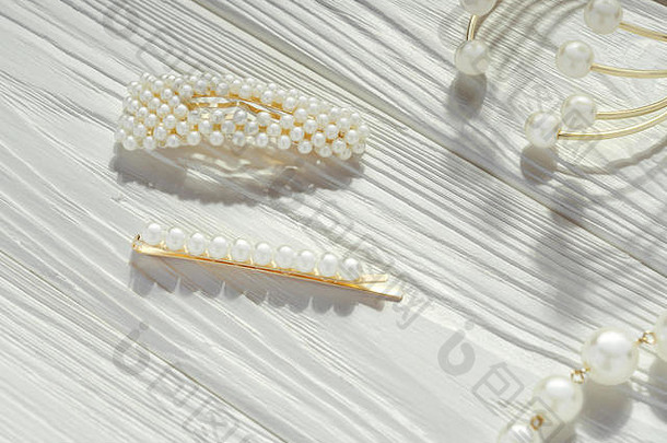 金珍珠发夹金手镯白色木表面
