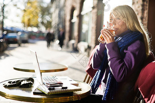年轻的女人坐着咖啡馆移动PC瑞典