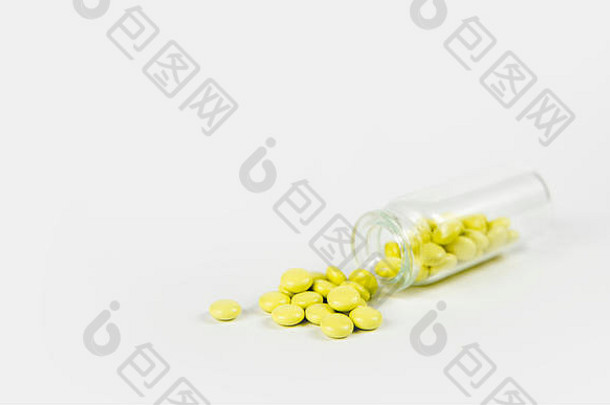 小玻璃Jar瓶下降了小黄色的缬草药片泄漏灰色的背景制药概念