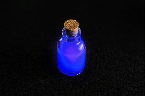 透明的瓶充满活力的蓝色的液体孤立的黑暗背景