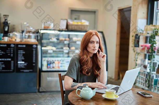 红色的头女孩手臂纹身坐着咖啡馆工作<strong>笔</strong>记本移动电话移动PC利物浦