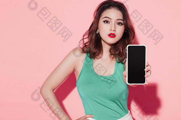 亚洲女孩显示智能手机屏幕粉红色的背景