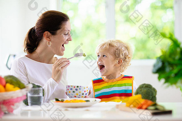 妈妈。喂养孩子蔬菜妈妈提要孩子白色厨房窗口婴儿男孩坐着高椅子吃健康的午餐蒸胡萝卜