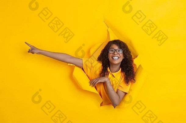 疯狂的快乐指出快乐的非裔美国人年轻的女人撕裂黄色的纸背景情感富有表现力的打破breakthrought概念人类情绪面部表达式销售