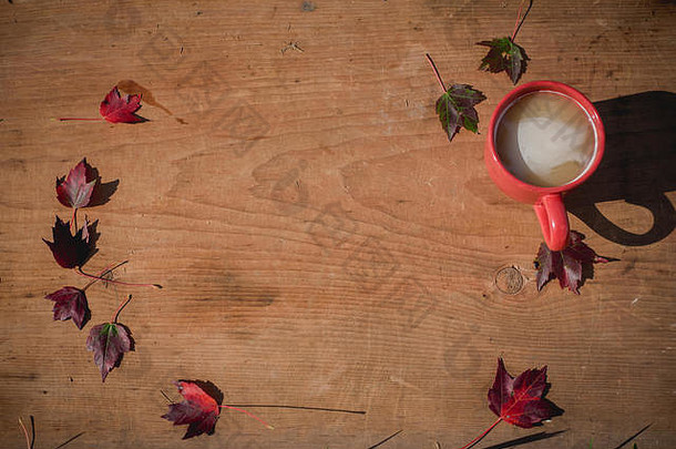 完整的杯温暖的茶坐在木表格包围秋天叶子