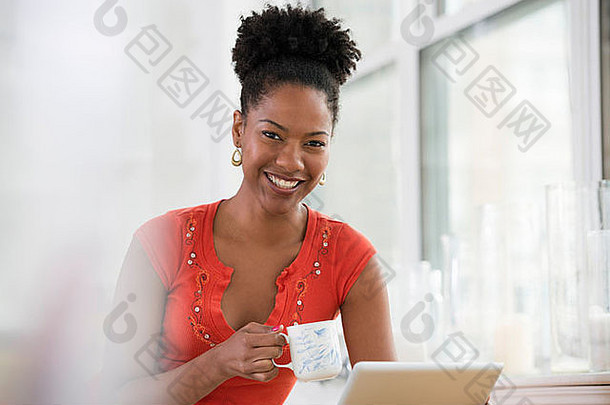 年轻的女人粉红色的衬衫数字平板电脑持有杯<strong>咖啡</strong>