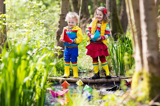 孩子们玩色彩斑斓的纸船小河阳光明媚的春天一天孩子们玩探索自然哥哥妹妹有趣的