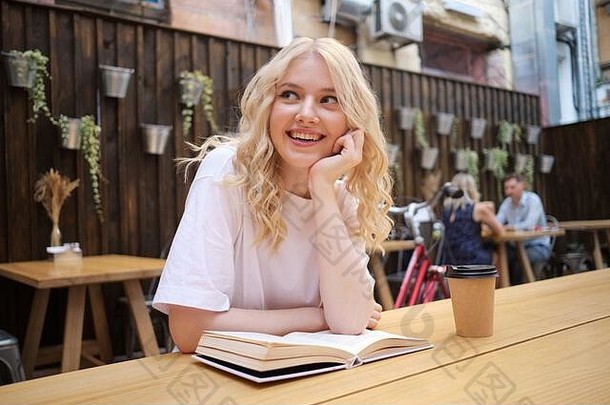漂亮的快乐的金发碧眼的女孩幸福的书咖啡表格院子里咖啡馆