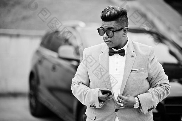 时尚的阿拉伯男人。夹克弓领带太阳镜黑色的运动型多功能车车阿拉伯丰富的商人移动电话