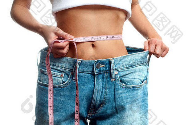 女人测量腰重量损失饮食概念女人超大的牛仔裤