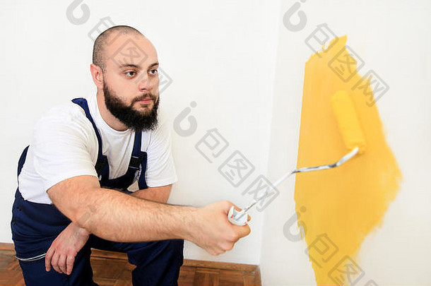 建设<strong>工人</strong>杂工完成改造公寓画家油漆辊刷绘画墙黄色的颜色